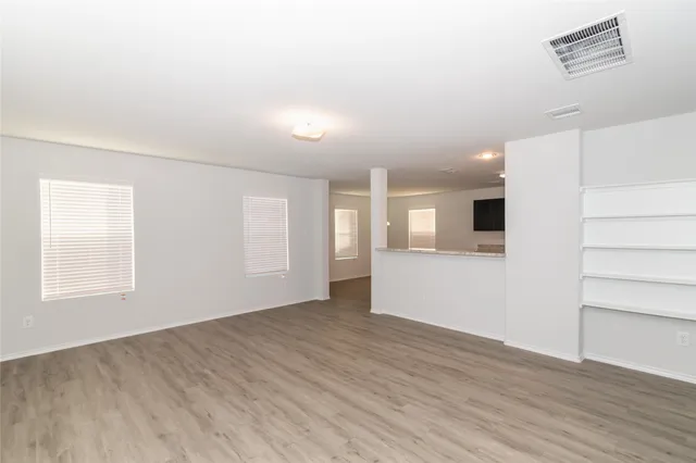 an empty room with wooden floor and windows