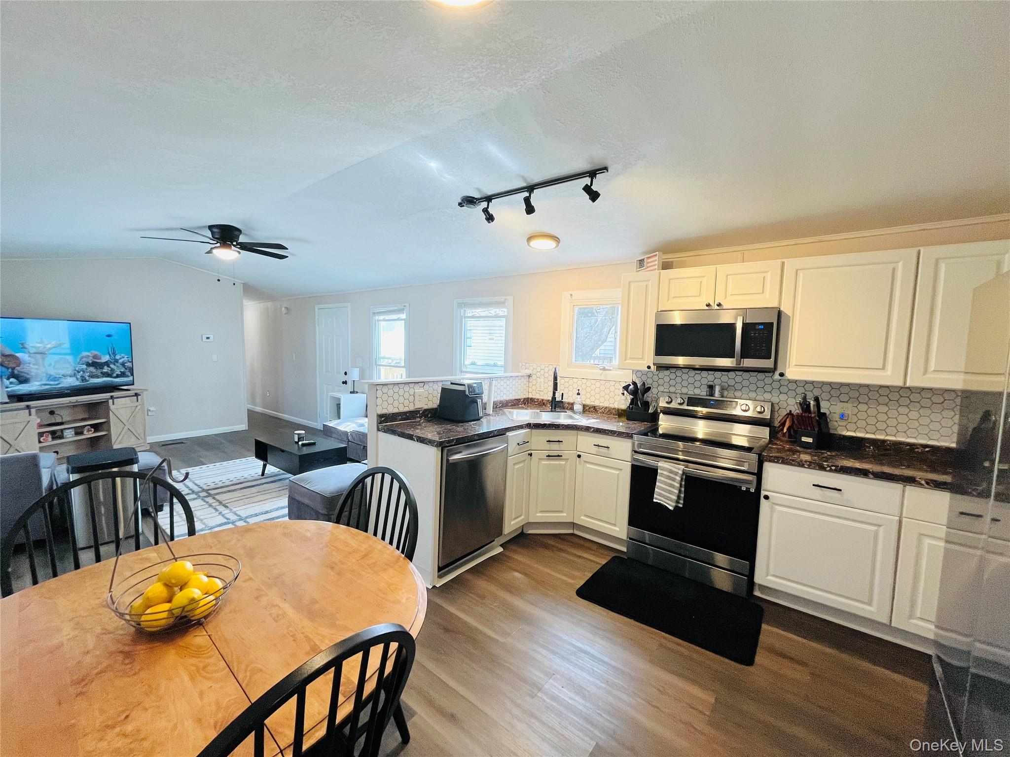 723 Beekman Road, Unit 42 Hopewell Junction, NY 12533 - Photo 8 of 16 a kitchen with granite countertop a stove top oven a sink dishwasher a dining table and chairs with wooden floor