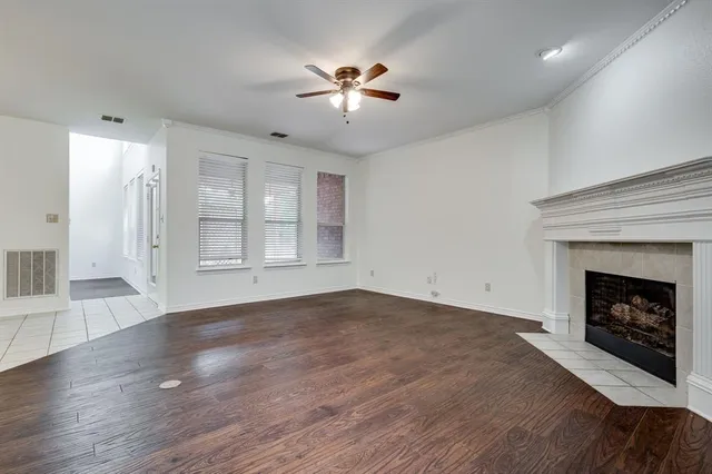 a view of an empty room with wooden floor fireplace and a window