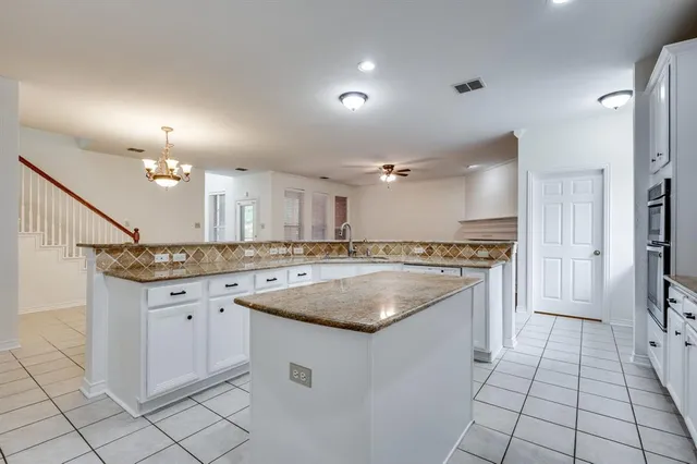 a kitchen with granite countertop a sink stove and cabinets