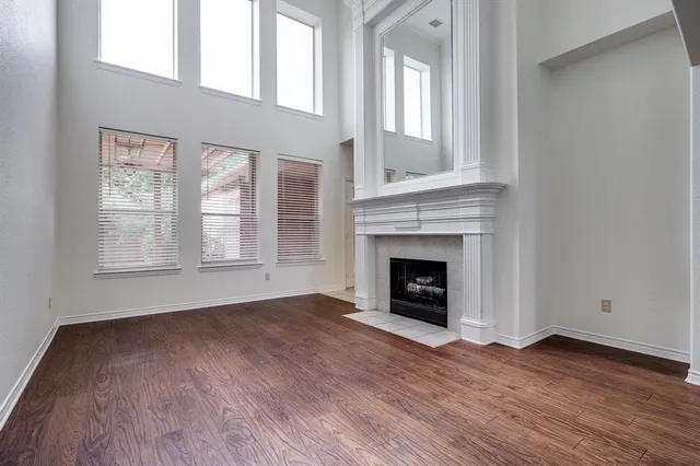 an empty room with wooden floor fireplace and windows