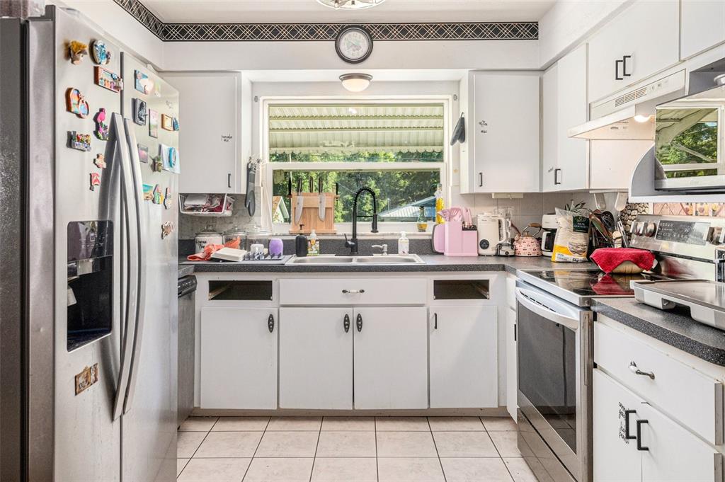 210 Red Rose Lane Inverness, FL 34452 - Photo 5 of 14 a kitchen with white cabinets and white appliances