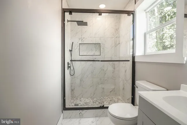 a bathroom with a shower a toilet and a window