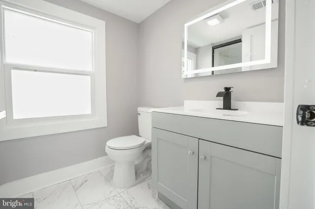 a bathroom with a toilet sink vanity and mirror