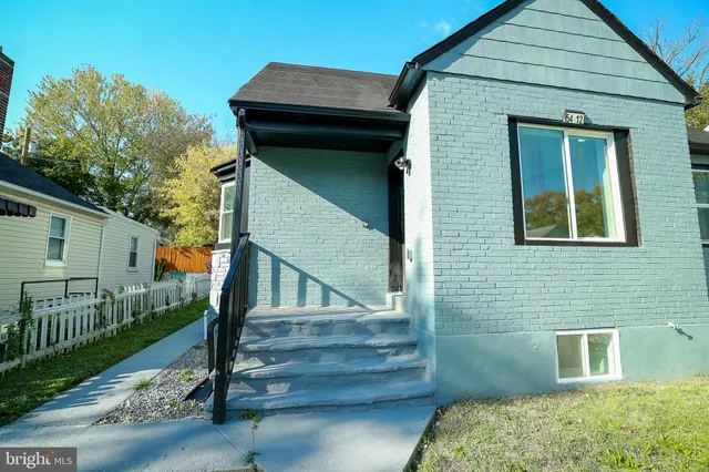 a yellow house with wooden fence next to a yard