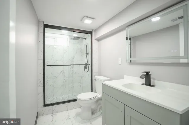 a bathroom with a shower sink vanity mirror and toilet