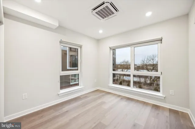 a view of an empty room with a window and wooden floor