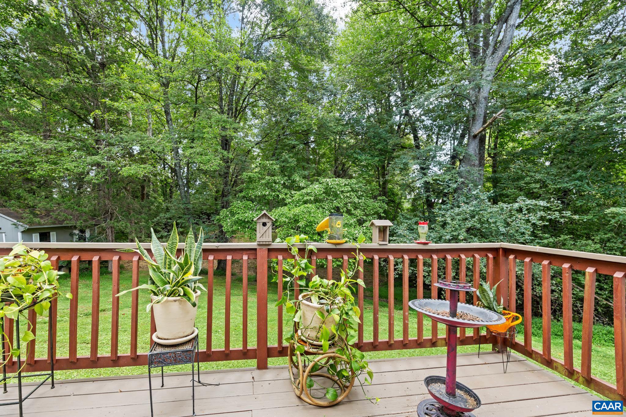 61 Snapdragon Road Ruckersville, VA 22968 - Photo 26 of 47 Enjoy peaceful outdoor living on this charming back deck! Featuring warm wooden railings, potted plants, a bird bath, and lush tree-lined backdrop, this serene oasis is perfect for relaxing, entertaining, and taking in nature right at home.