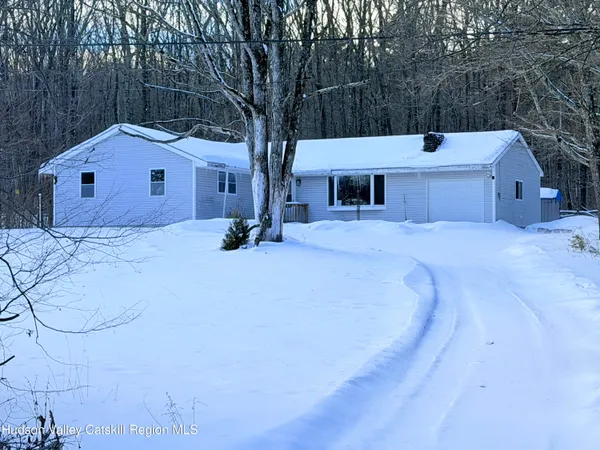 a front view of house with yard and trees in the background