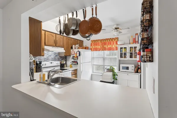 a kitchen with stainless steel appliances granite countertop a sink a stove a refrigerator a washer dryer and white cabinets