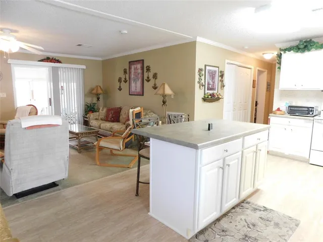 a living room with stainless steel appliances kitchen island granite countertop a sink and a refrigerator