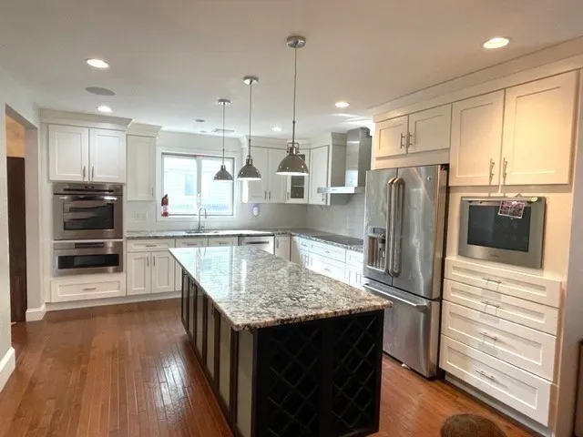 a kitchen with stainless steel appliances granite countertop a refrigerator a stove and a sink