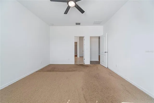 an empty room with a ceiling fan and window