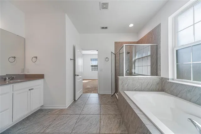 a spacious bathroom with a granite countertop sink a mirror and a bathtub
