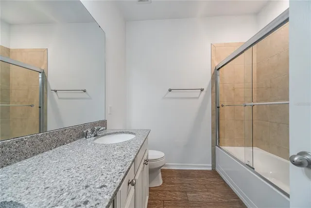 a bathroom with a granite countertop sink a toilet and shower