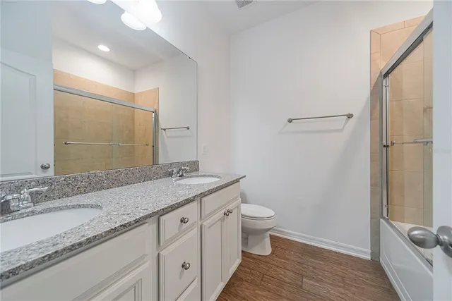 a bathroom with a granite countertop sink a toilet and a large mirror
