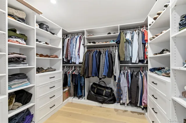 a view of walk in closet with clothes and shoes