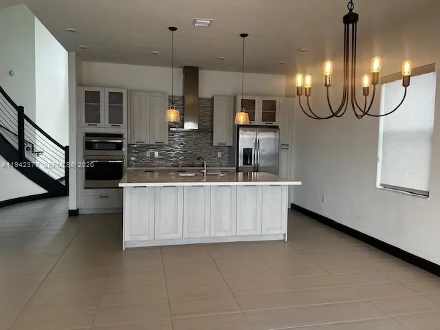 a kitchen with stainless steel appliances kitchen island granite countertop a refrigerator a oven a sink and a counter top space