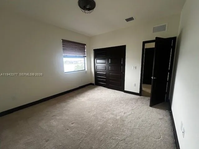 an empty room with closet and windows