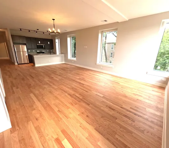 a kitchen with stainless steel appliances wooden floors wooden cabinets a refrigerator and a sink