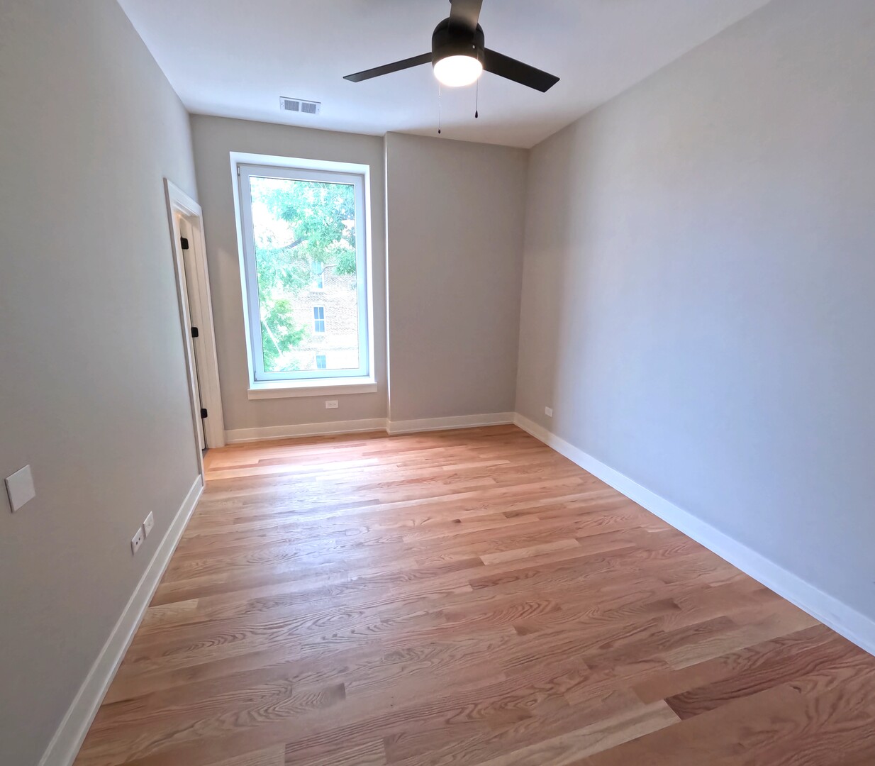 2100 West 18th Place, Unit 301 Chicago, IL 60608 - Photo 9 of 13 an empty room with wooden floor chandelier fan and windows