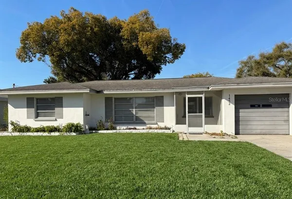 a front view of a house with a yard and trees