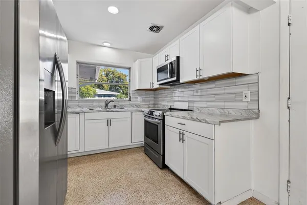 a kitchen with stainless steel appliances granite countertop a refrigerator sink and cabinets