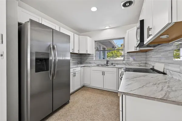a kitchen with a refrigerator sink and cabinets