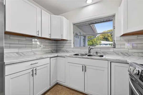 a kitchen with white cabinets sink and window