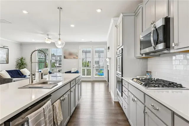 a kitchen with stainless steel appliances a sink a stove cabinets and a wooden floor