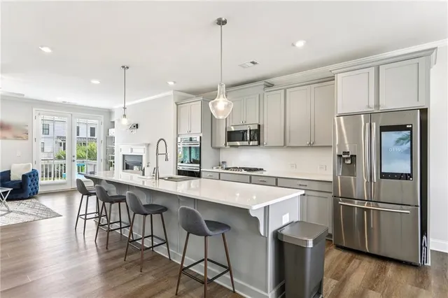 a kitchen with stainless steel appliances a refrigerator a sink a stove a dining table and chairs