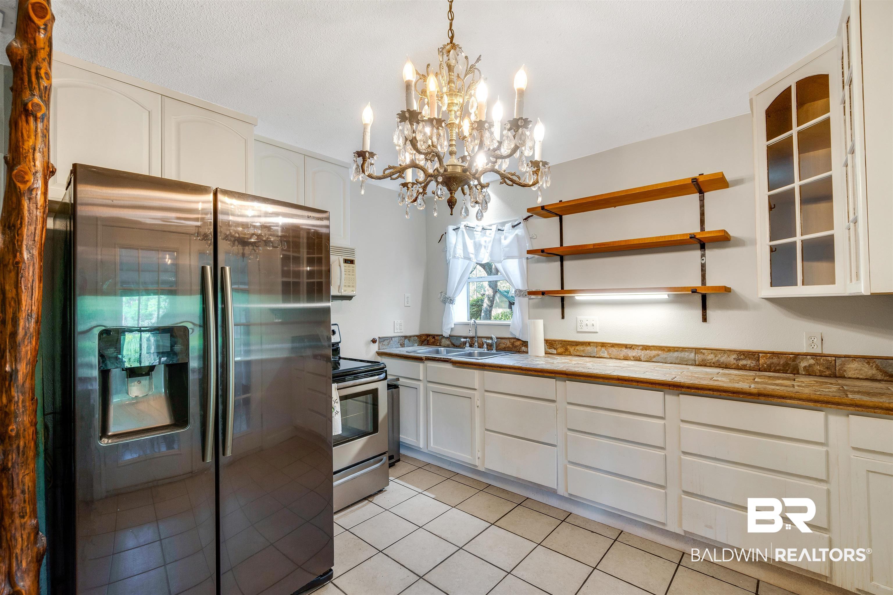 34341 Lost River Road Seminole, AL 36574 - Photo 9 of 36 Kitchen featuring stainless steel appliances, light tile patterned flooring, a chandelier, pendant lighting, and white cabinets