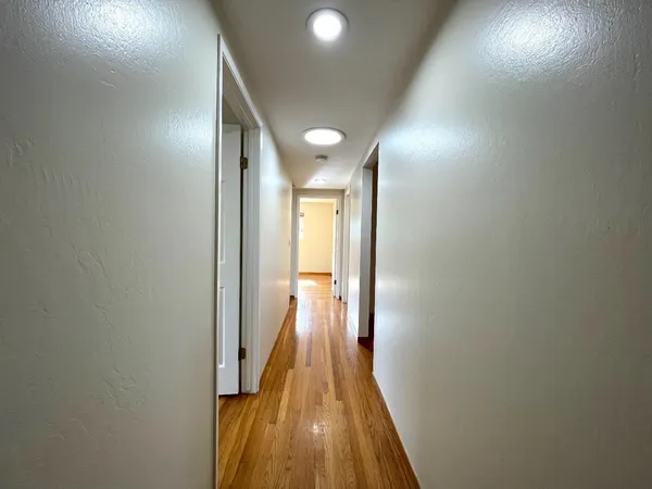 a view of a hallway with wooden floor and staircase