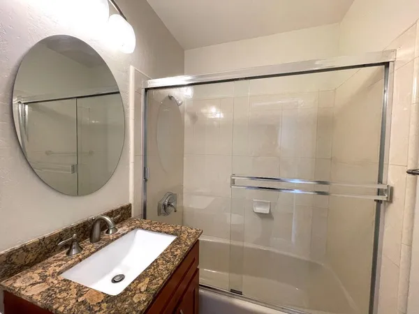 a bathroom with a sink vanity mirror and a shower