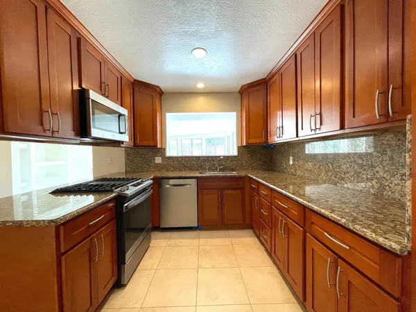 a kitchen with stainless steel appliances granite countertop wooden cabinets a stove top oven with granite countertops and cabinets