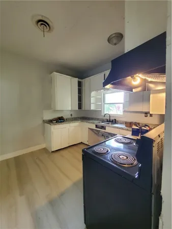 a kitchen with kitchen island granite countertop a sink cabinets and stainless steel appliances