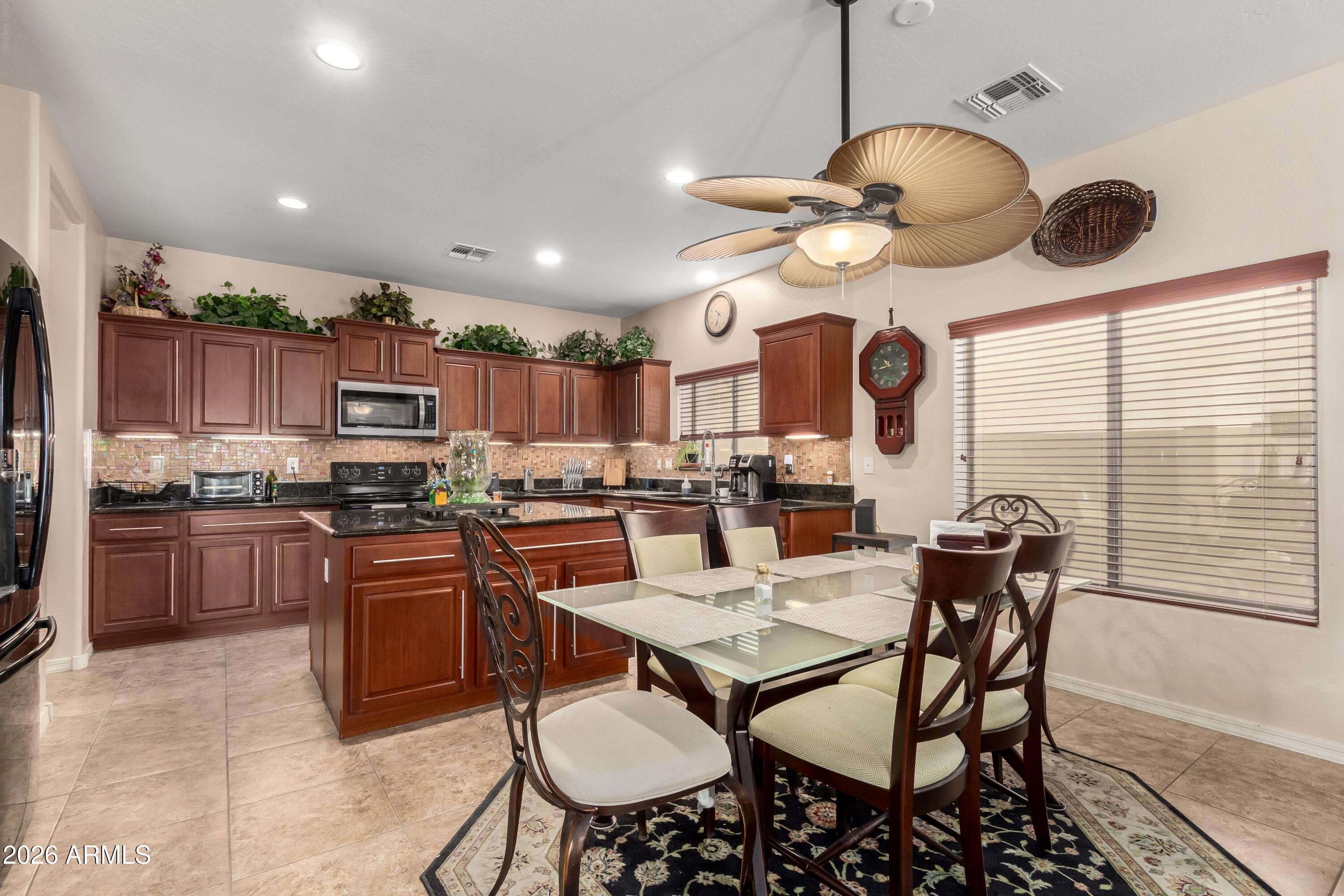 19221 North Toya Street Maricopa, AZ 85138 - Photo 12 of 22 a kitchen with stainless steel appliances granite countertop a stove a sink dishwasher a dining table and chairs with wooden floor