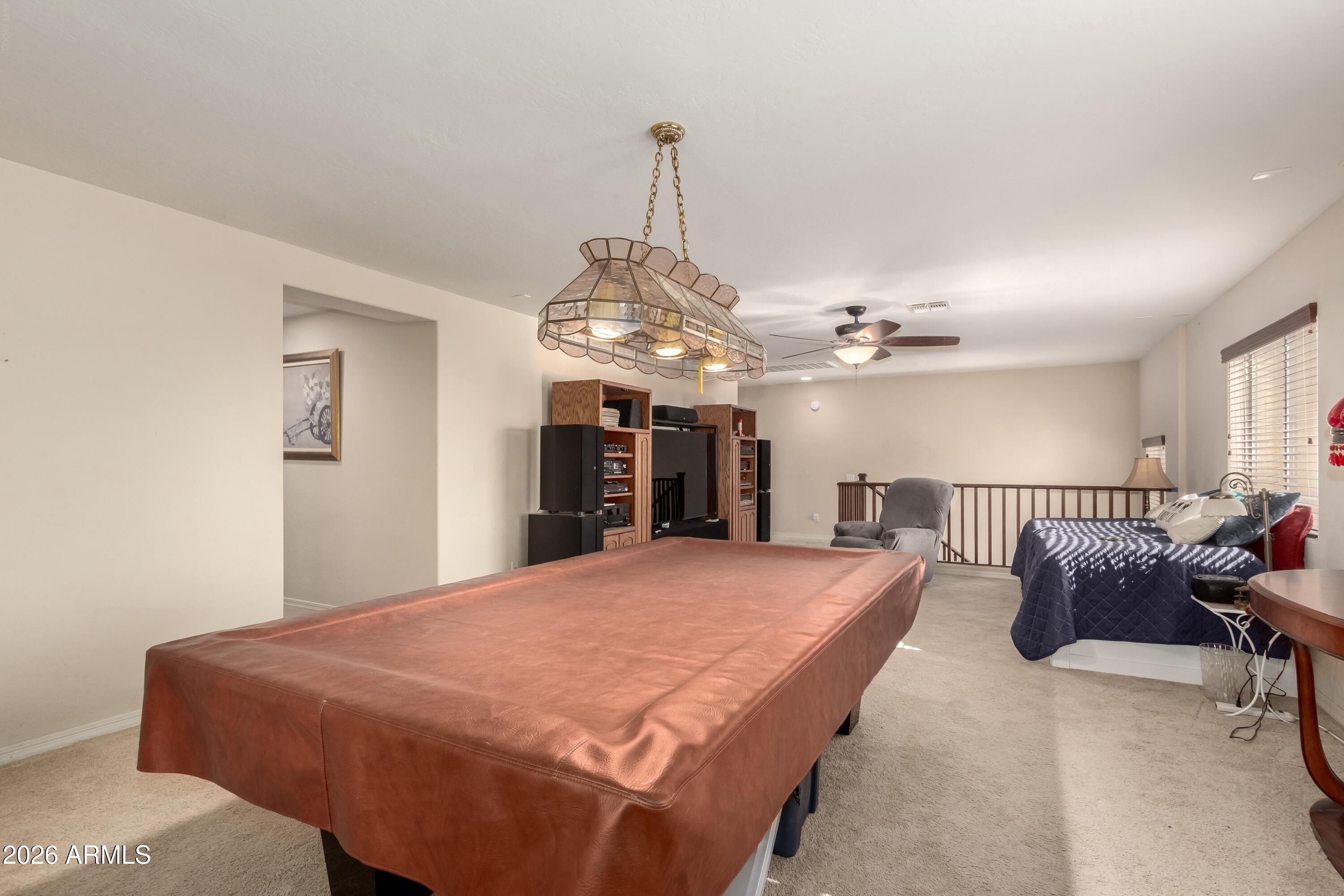 19221 North Toya Street Maricopa, AZ 85138 - Photo 15 of 22 a spacious bedroom with a bed a chandelier and a dresser