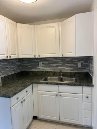 a kitchen with granite countertop white cabinets and a sink