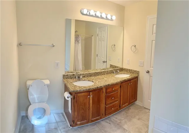a bathroom with a granite countertop sink a toilet and a mirror