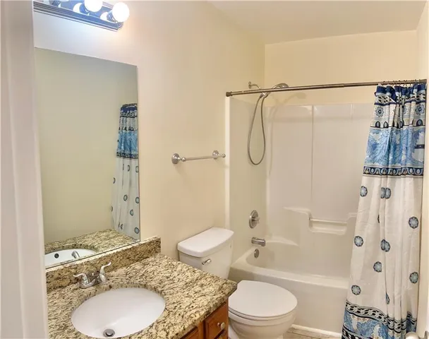 a bathroom with a granite countertop sink toilet a mirror and shower