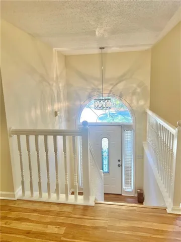 a view of a livingroom with a chandelier wooden floor table and chairs