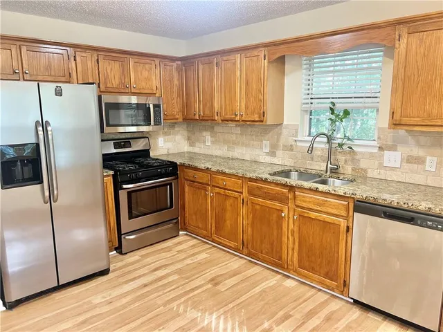 a kitchen with granite countertop white cabinets and stainless steel appliances