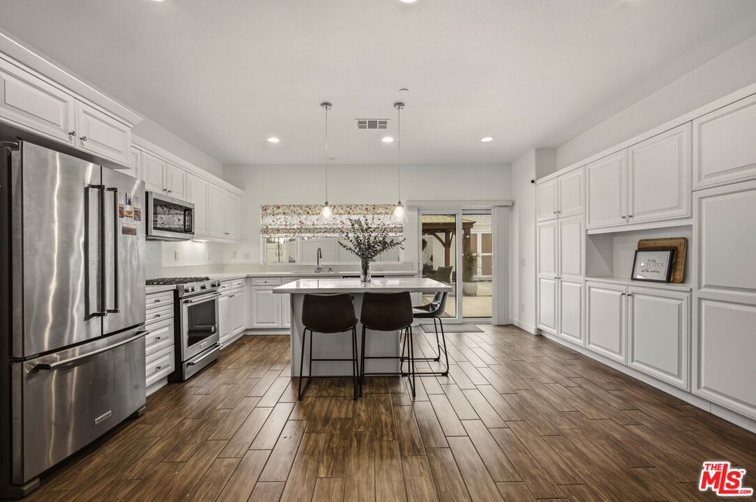 3065 Gibson Street Riverside, CA 92503 - Photo 9 of 15 a kitchen with stainless steel appliances kitchen island granite countertop a stove top oven a sink dishwasher a dining table and chairs with wooden floor