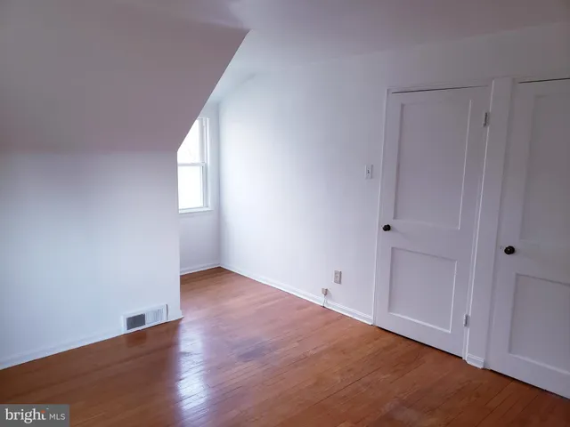 a view of an empty room with wooden floor and window