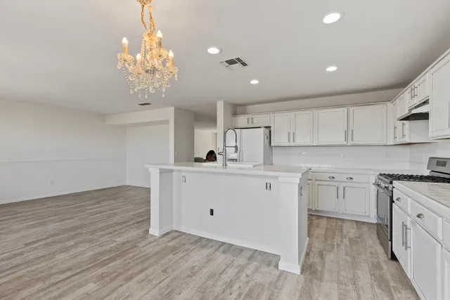 a kitchen with cabinets wooden floor and stainless steel appliances
