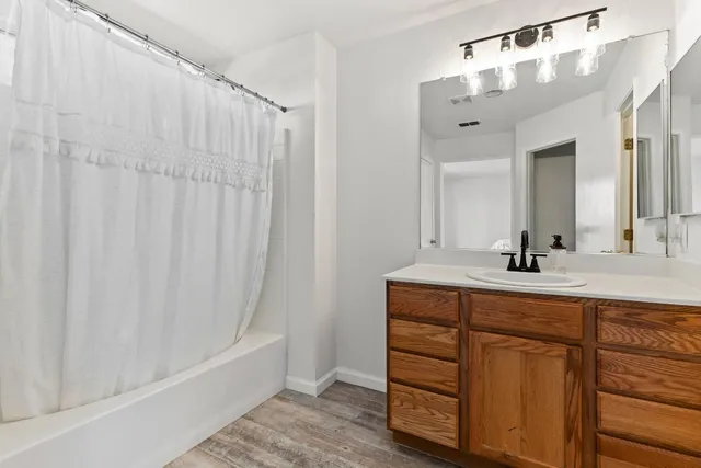 a bathroom with a double vanity sink a mirror a bathtub and shower