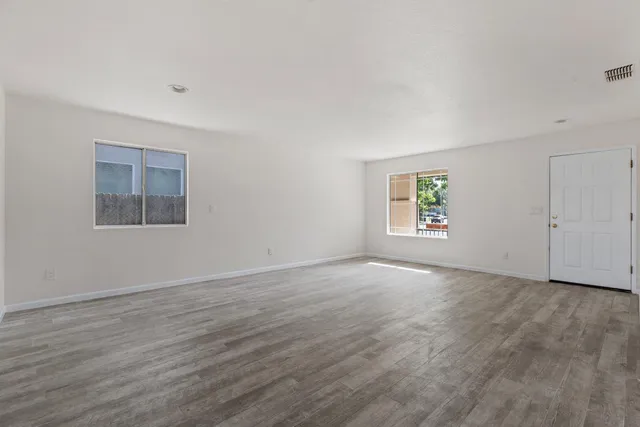 a view of an empty room with a window and wooden floor