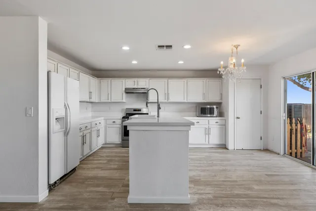 a large kitchen with white cabinets stainless steel appliances and a center island
