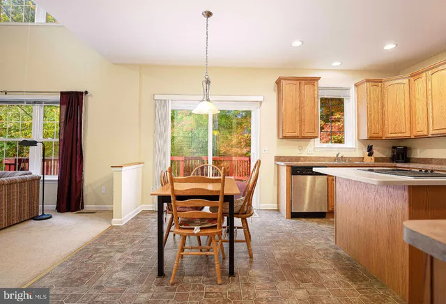 a kitchen with stainless steel appliances granite countertop a stove top oven a refrigerator a sink and a dining table with chairs